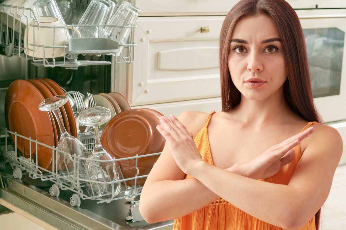 piatti in lavastoviglie aperta e donna braccia incrociate