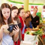 Ragazza in coda alla cassa del supermercato cerca soldi nel portafogli