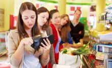 Ragazza in coda alla cassa del supermercato cerca soldi nel portafogli