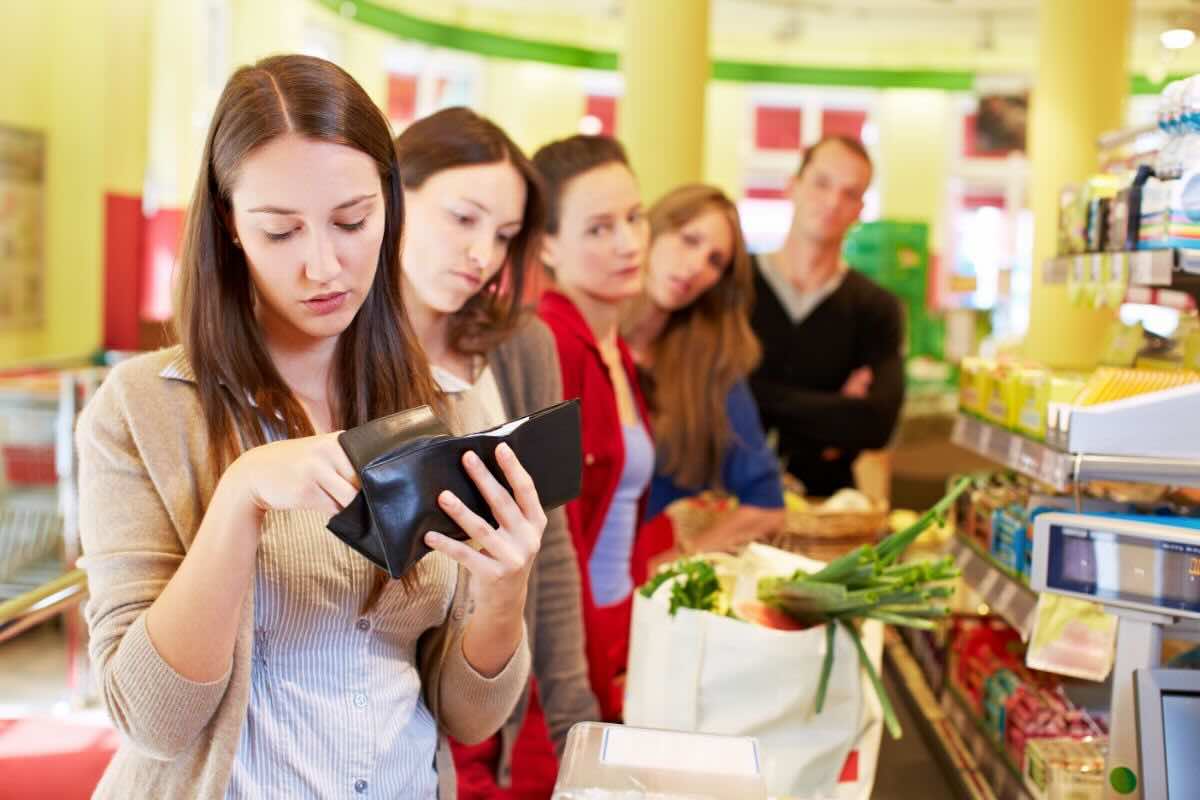 Ragazza in coda alla cassa del supermercato cerca soldi nel portafoglio