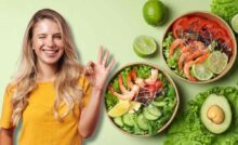 Ragazza che fa occhiolino e ok con la mano, di fianco a lei bow con insalate, sul tavolo insalata, lime e avocado